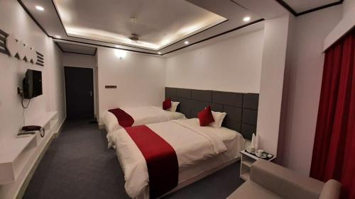 a hotel room with two beds and a television at The Grand Mafi Hotel & Suites in Sylhet