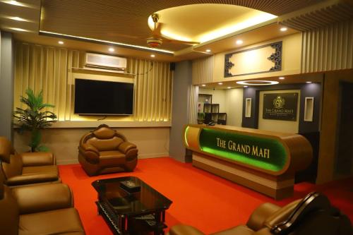 a living room with a tv and a couch and chairs at The Grand Mafi Hotel & Suites in Sylhet