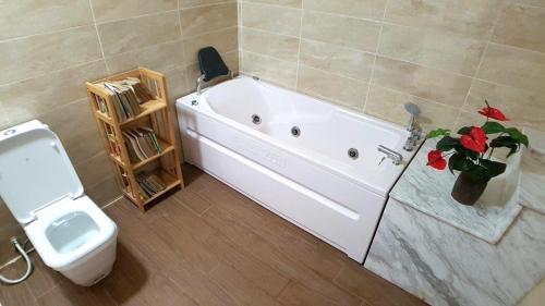 ein Badezimmer mit einer Badewanne neben einem WC in der Unterkunft Brick Home Villa Sóc Sơn - Venue Travel in Hanoi