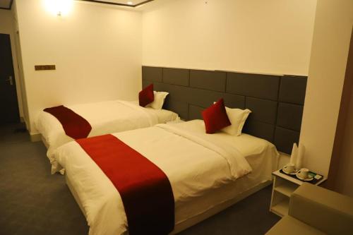 two beds in a hotel room with red and white at The Grand Mafi Hotel & Suites in Sylhet