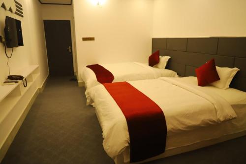 a hotel room with two beds and a television at The Grand Mafi Hotel & Suites in Sylhet