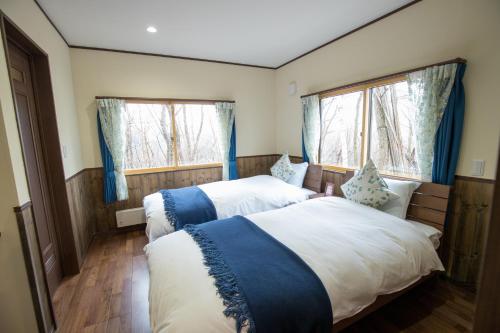 two beds in a room with two windows at Kudo's Lodge in Hakuba