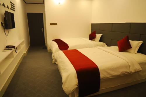 a hotel room with two beds and a television at The Grand Mafi Hotel & Suites in Sylhet