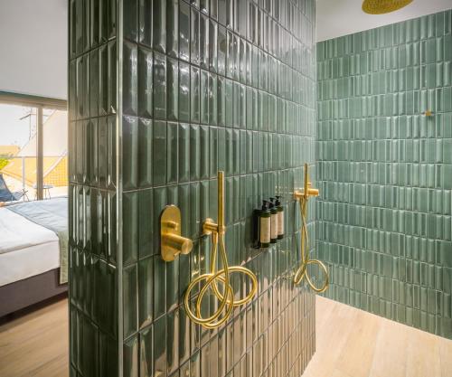 a bathroom with green tiled walls and gold handles at Van der Valk Hotel Hildesheim in Hildesheim