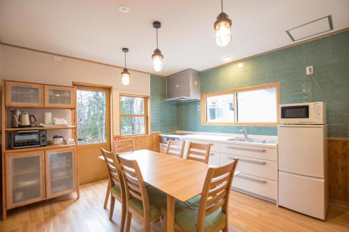 eine Küche mit einem Holztisch und Stühlen in der Unterkunft Kudo's Lodge in Hakuba