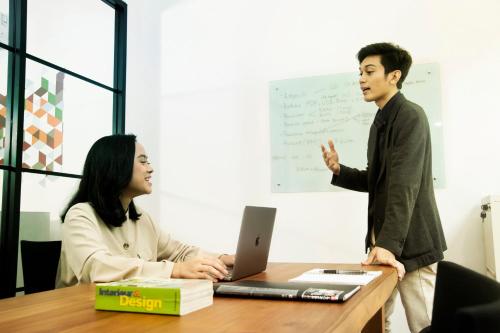 a man and a woman sitting at a table with a laptop at Tuju Arteri Pods in Jakarta