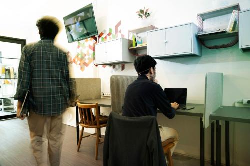 two men sitting at a desk with a laptop at Tuju Arteri Pods in Jakarta