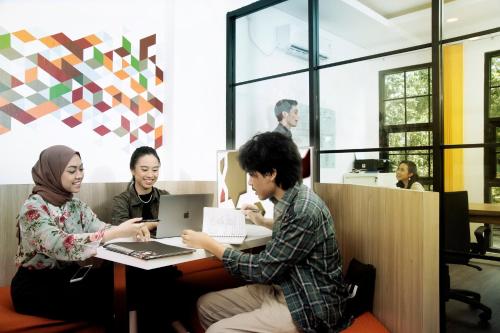 a group of people sitting at a table with a laptop at Tuju Arteri Pods in Jakarta
