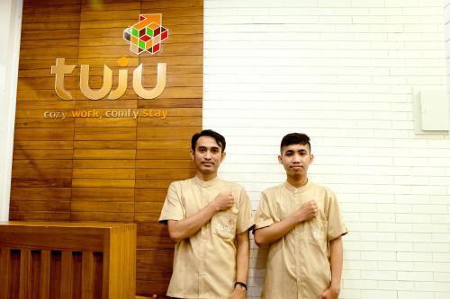 two men are standing in front of a wall at Tuju Arteri Pods in Jakarta