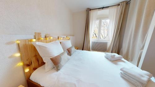 une chambre avec un lit avec des draps blancs et une fenêtre dans l'établissement Le Neubau, à Colmar