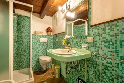 uma casa de banho com azulejos verdes, um lavatório e um WC. em Emerald Top in Old Town by sea em Alghero