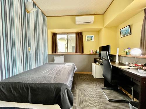 ein Hotelzimmer mit einem Bett, einem Schreibtisch und einem Computer in der Unterkunft Time Rich in Okinawa