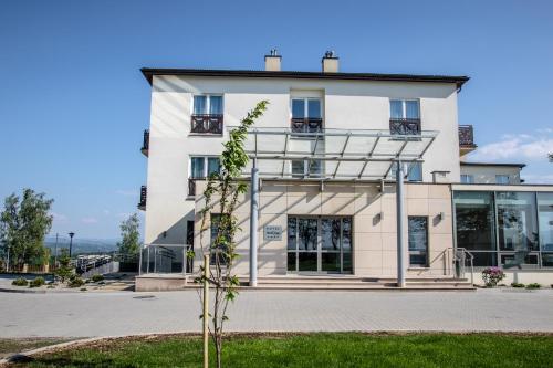 a building with a tree in front of it at Hotel Radocza Park Business in Radocza