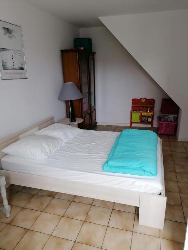 - une chambre avec un lit blanc et une couverture bleue dans l'établissement Chez pépé, à Barbâtre