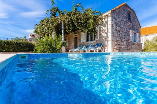 a swimming pool with blue water in front of a house at Green Garden House in Korčula