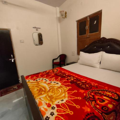 a bedroom with a bed with a red and yellow blanket at Hotel Shannti Inn in Varanasi