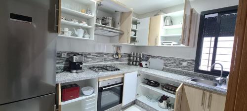 eine Küche mit weißen Arbeitsflächen, einer Spüle und einem Kühlschrank in der Unterkunft SuperAppart KENITRA in Kenitra