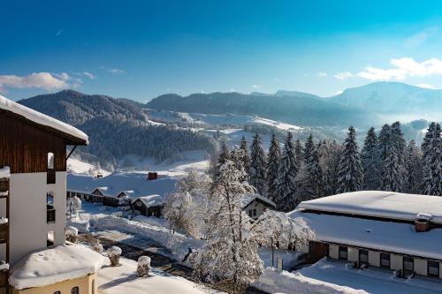 a snow covered mountain with trees and a building at MONDI Resort und Chalet Oberstaufen in Oberstaufen