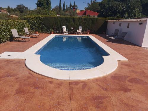una piscina con sillas y una mesa en un patio en Villa Alcor, en Beas