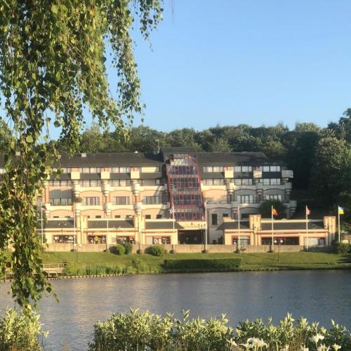 a large building in front of a river at Hôtel Spa Du Béryl in Bagnoles de l'Orne