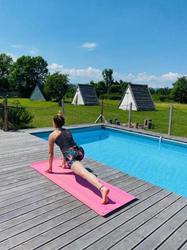 a young girl doing a yoga pose in front of a pool at GreenValleyGlamping in Šešče pri Preboldu