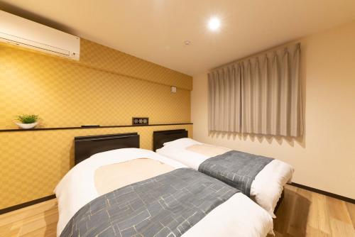 Duas camas num quarto com paredes amarelas em スタジオーネ 箱根強羅 East - Stagione Hakone Gora East em Hakone