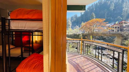 a room with a balcony with bunk beds and a view at Madpackers Jibhi - Of Streamsides & Waterfalls in Jibhi
