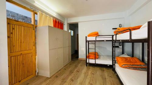 a room with three bunk beds and a door at Madpackers Jibhi - Of Streamsides & Waterfalls in Jibhi