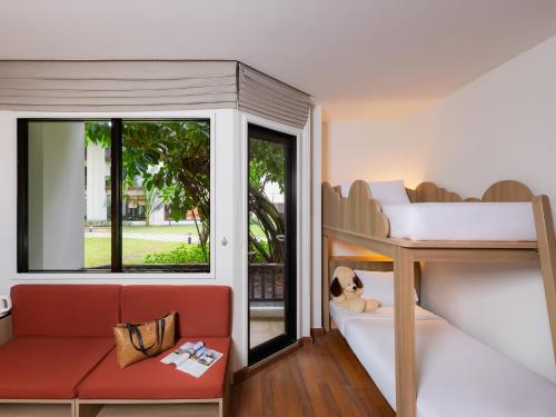 a room with a bunk bed and a couch and a window at Hotel Ibis Samui Bophut in Bophut