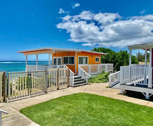 a yellow house with a white fence and the ocean at Mokulē'ia Beach Houses at Owen's Retreat in Waialua