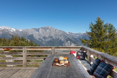 a picnic table on a deck with mountains in the background at Chalet La Tsoum in Riddes