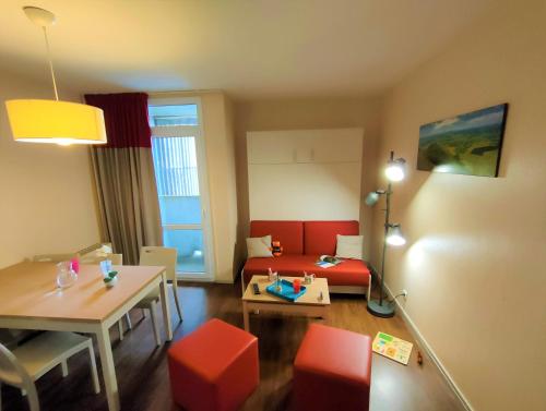 a small living room with a red couch and a table at VVF Super-Besse Auvergne Sancy in Super Besse
