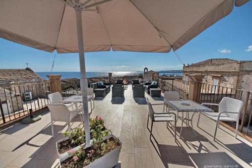 a patio with tables and chairs and an umbrella at Regina Margherita B&B in Marzamemi