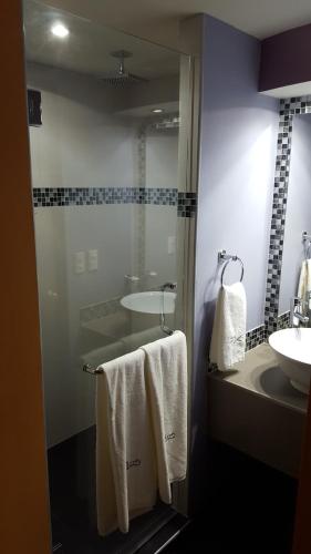 a bathroom with a sink and a shower with towels at Motel Las Dunas in Mexicali