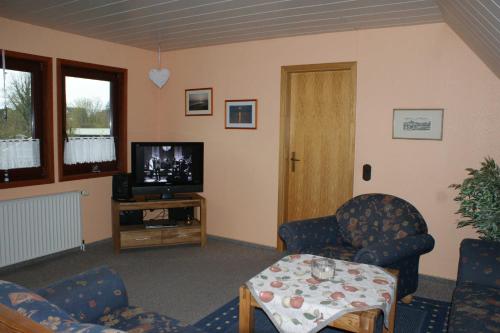 Una sala de estar con sillas, un televisor y una mesa. en Dat hyggelige Ferienhus in Kappeln, en Kappeln