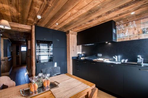 a kitchen with black cabinets and a wooden ceiling at Paccard Locations Chamonix in Chamonix