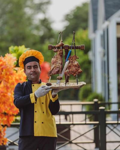 a man is holding a tray of food on a plate at Mehsul Recreational Center in İsmayıllı