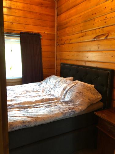 a bed in a log cabin with a window at Mysig timmerstuga med braskamin nära Hovfjället in Torsby