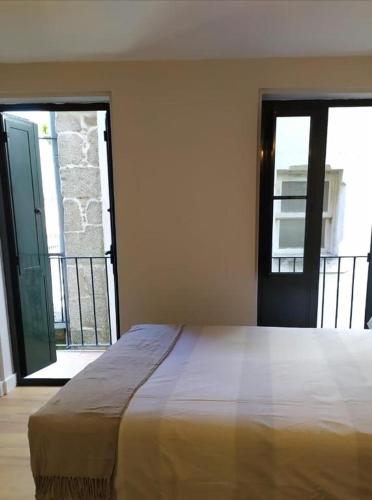 a bedroom with a large bed and a balcony at Estudio Casco Vello in Vigo