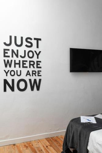 a bedroom with a wall with a sign that says just enjoy where you are now at Mapango Small Rooms in Santa Cruz de Tenerife