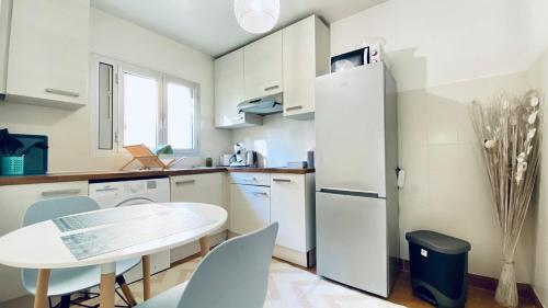 une cuisine avec une table et un réfrigérateur blanc dans l'établissement Le Châtaignier Modern center parking garden, à Antibes
