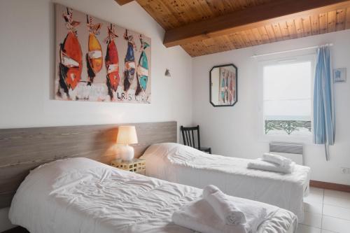 ラ・フロットにあるMaison Trémiereのベッドルーム1室(ベッド2台付)、壁にサーフボード付きの窓が備わります。