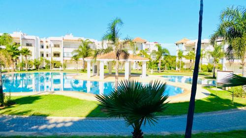 a resort pool with a gazebo and palm trees at Chez Marya Asilah Marina Golf uniquement famille in Asilah