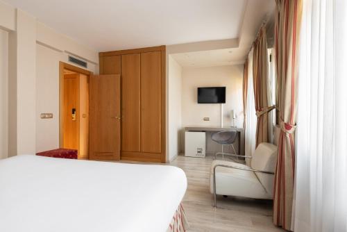 a bedroom with a bed and a chair and a television at Crisol Almirante Bonifaz in Burgos