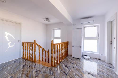 a white room with a wooden staircase and a window at Butterfly Homes - Apartament stil duplex Mamaia Nord in Năvodari