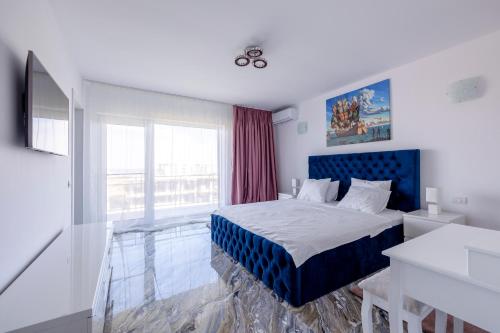 a bedroom with a blue bed and a window at Butterfly Homes - Apartament stil duplex Mamaia Nord in Năvodari