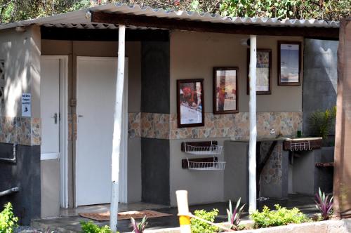 a small house with a porch and a white door at Victoria Falls Backpackers Lodge- Camp Sites in Victoria Falls