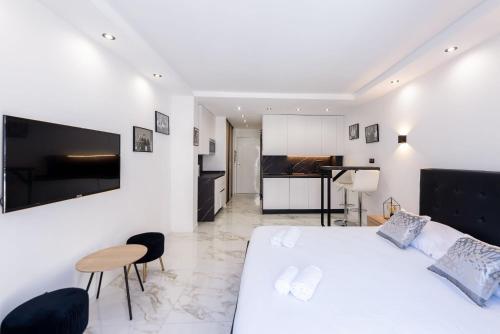 - une chambre blanche avec un grand lit et une cuisine dans l'établissement Large studio - 50m Cannes beach - terrace sea view, à Cannes
