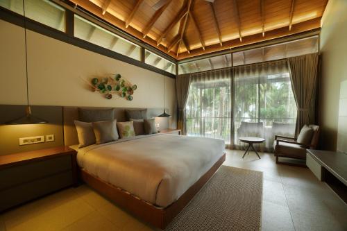 a bedroom with a large bed and a living room at Tilar Siro Andamans - CGH Earth in Havelock Island