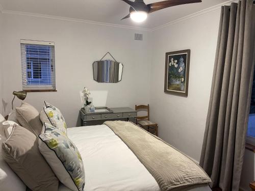 a bedroom with a bed and a table with a ceiling fan at Villa Voigt in Hermanus